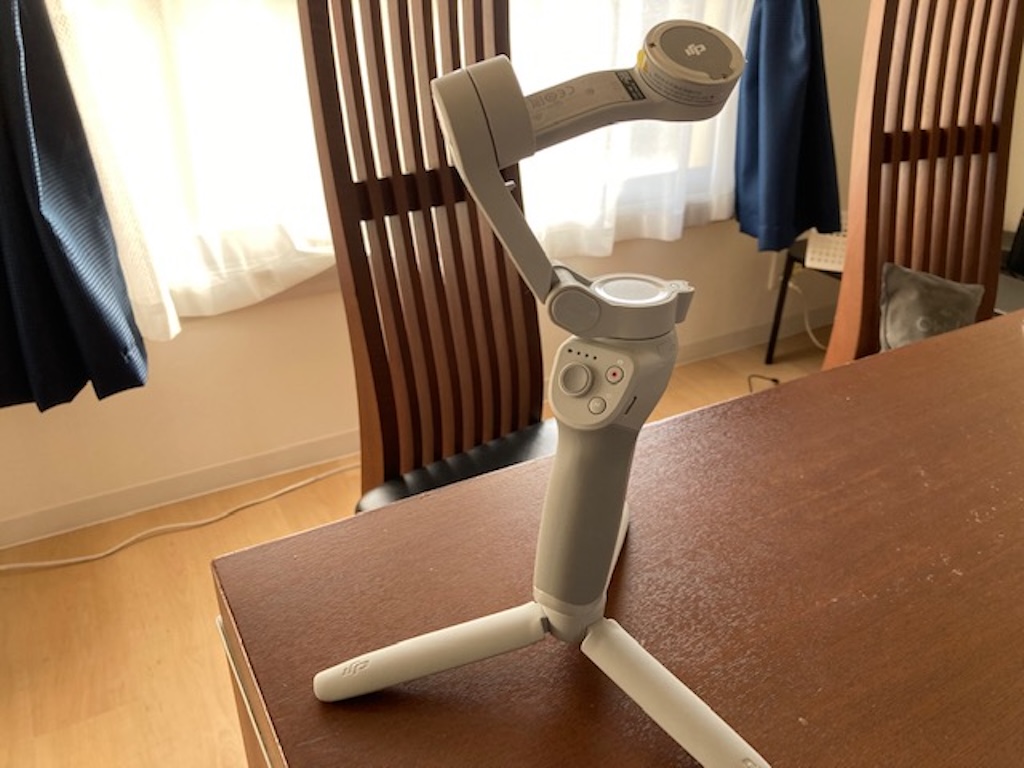三脚を開いて自立設置されたDJI Osmo Mobileシリーズのスマートフォン用ジンバル
