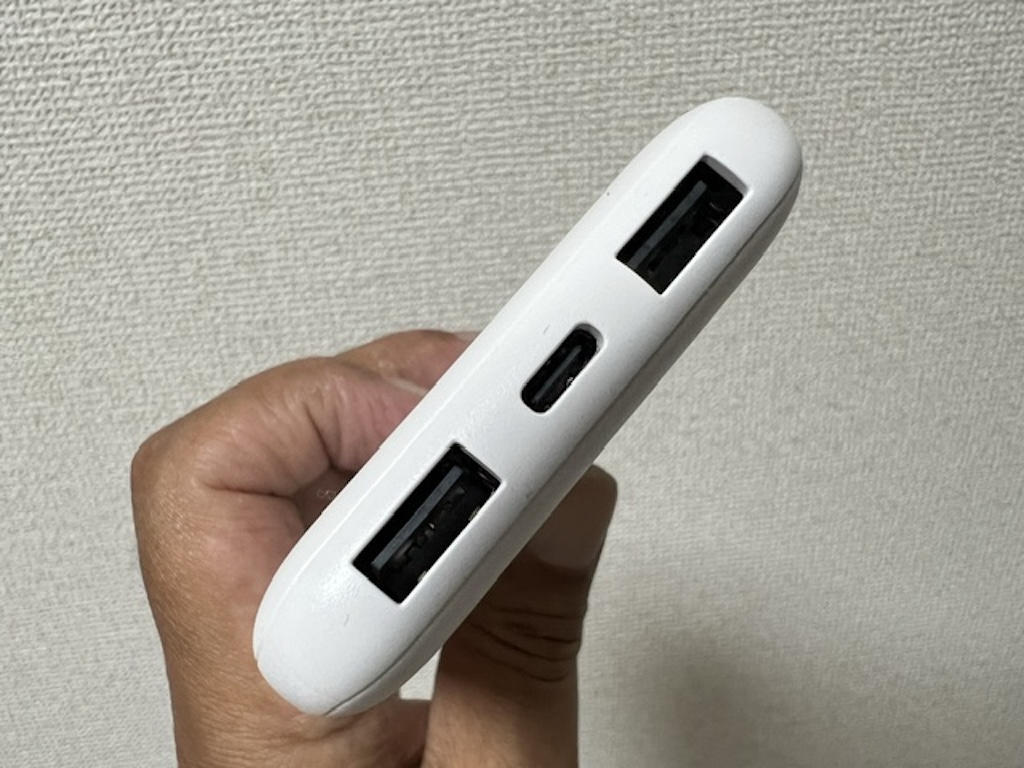 手に持ったエレコム モバイルバッテリー DE-C66-10000の出力ポート部分。2つのUSB-Aポートと中央のUSB Type-Cポート
